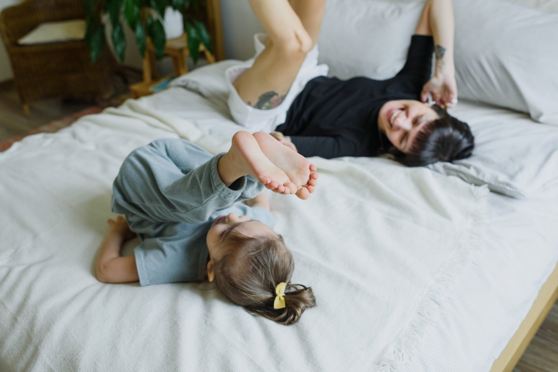 cheerful young mother with little child having fun on bed