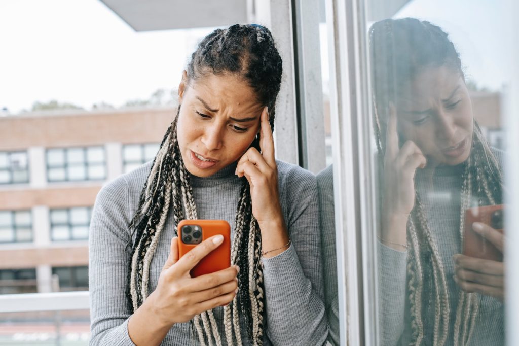 tired black woman browsing mobile phone