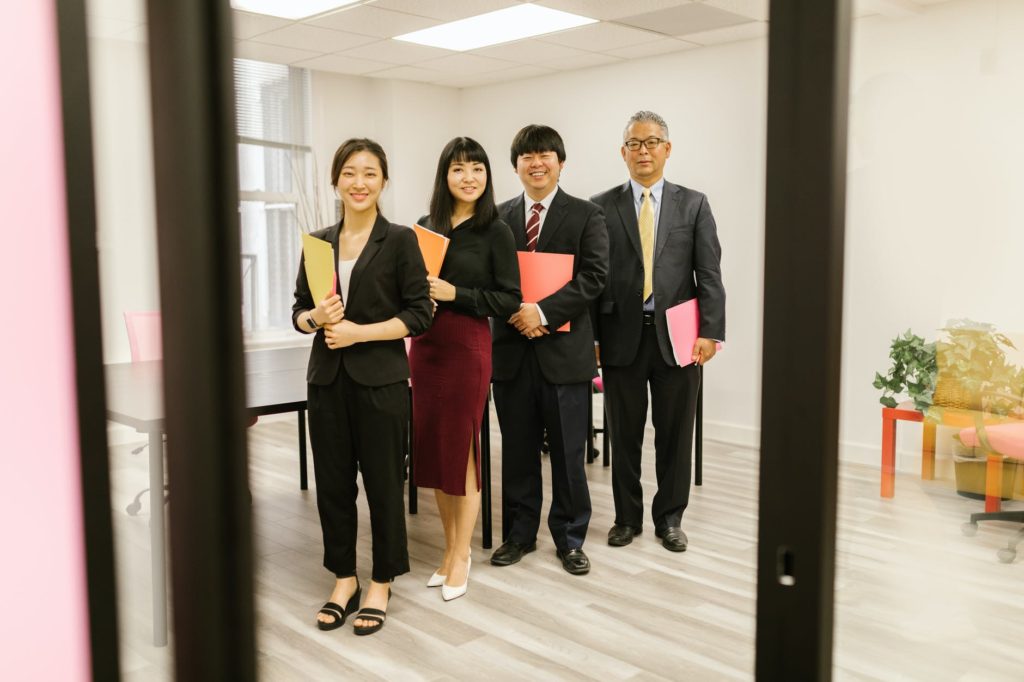 men and women standing in room holding folders